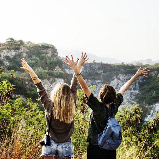 Zwei Frauen heben ihre Hände in die Luft und zeigen Freude und Begeisterung.