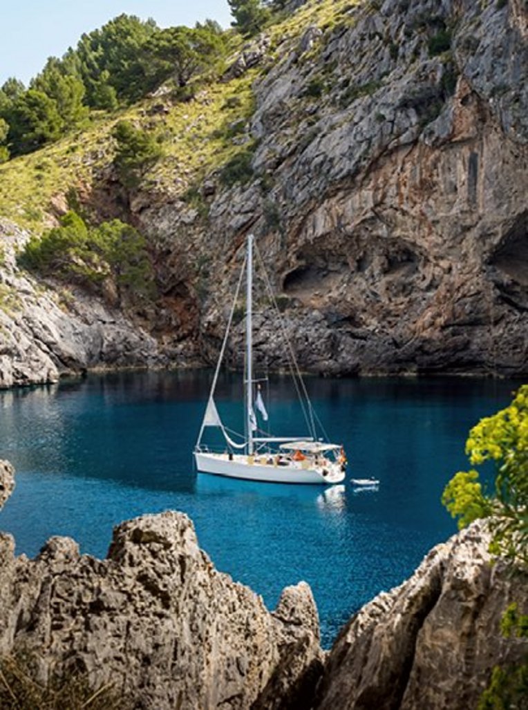Ein Boot schwimmt in einem blauen Gewässer vor der Küste Mallorcas.