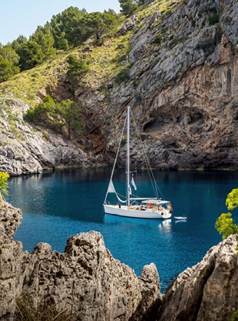 Ein Boot schwimmt in einem blauen Gewässer vor der Küste Mallorcas.