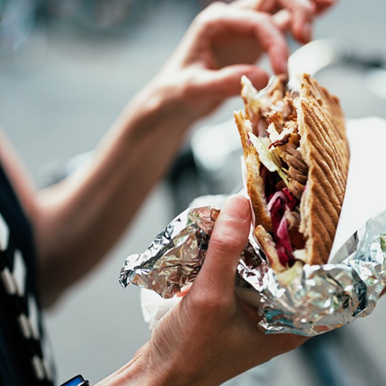 Eine Person hält ein Sandwich in der Hand, während sie in Berlin steht.