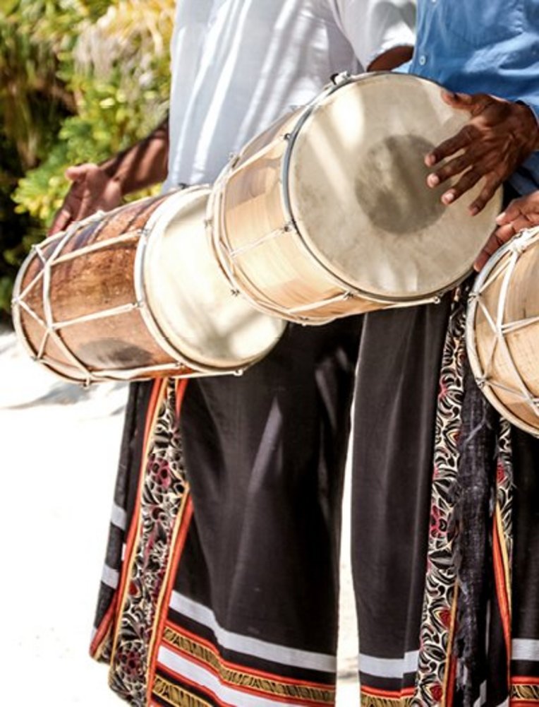 Am Strand spielt eine Gruppe von Männern rhythmisch auf ihren Trommeln und schafft eine lebhafte Atmosphäre.