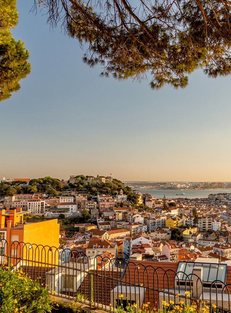 Blick auf die Stadt Lissabon, Portugal, mit ihren bunten Gebäuden und dem Fluss Tejo im Hintergrund.