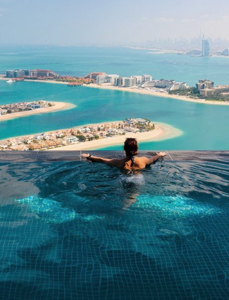 Eine Frau sitzt in einem Pool mit Blick auf den Ozean in Dubai.