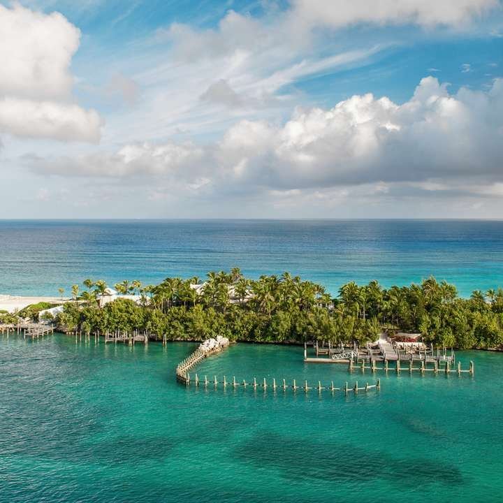 Eine Insel in den Bahamas mit einem kleinen Haus und einem Steg, umgeben von klarem, blauem Wasser.