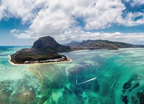 Luftaufnahme eines Riffs und einer Insel vor der Küste von Mauritius, mit klarem Wasser und bunten Korallen.
