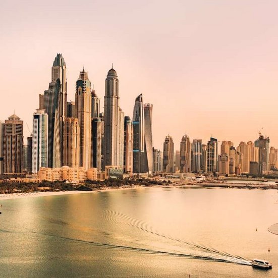 Blick von oben auf die Dubai-Skyline, reflektiert im Wasser, mit modernen Wolkenkratzern und strahlendem Himmel.
