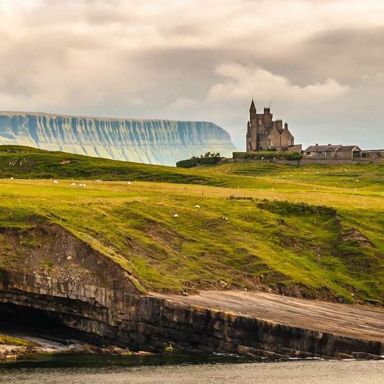 Eine Burg auf einem Hügel mit Blick auf den Ozean in Irland.