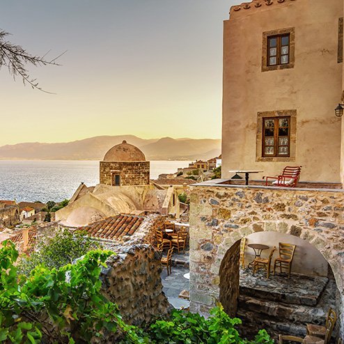  Ein altes Steinhaus mit Blick auf das Meer bei Sonnenuntergang in Griechenland.