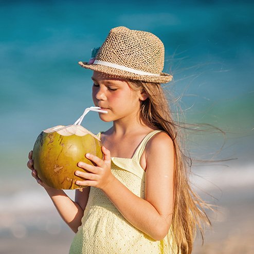 petite fille buvant dans une noix de coco sur la plage.