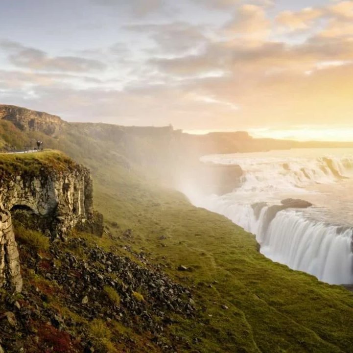 Paysage islandais au coucher du soleil, avec des montagnes et des nuages colorés illuminés par la lumière dorée.