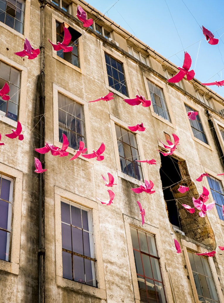 Ein Gebäude in Lissabon mit rosa Vögeln, die fröhlich in der Luft fliegen.