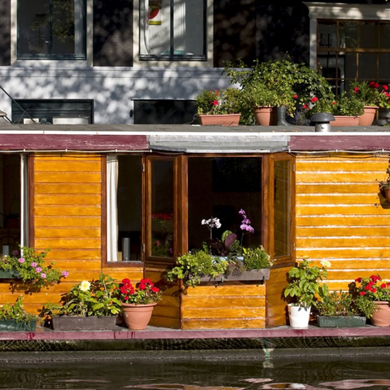 Ein Hausboot in Amsterdam, geschmückt mit bunten Blumen, schwimmt friedlich auf dem Wasser.