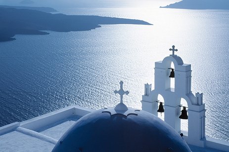 Weisse griechische Glocke über dem Meer, mit Blick auf die blaue Weite und den klaren Himmel.