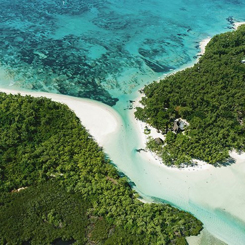 Luftaufnahme von Mauritius: eine tropische Insel mit weißem Sand und grünen Bäumen, die das Paradies verkörpern.