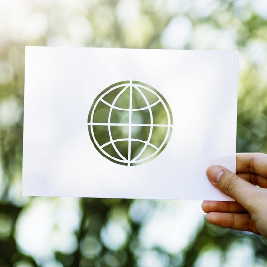 Eine Person hält ein Blatt Papier mit einer Weltkugel darauf in der Hand.