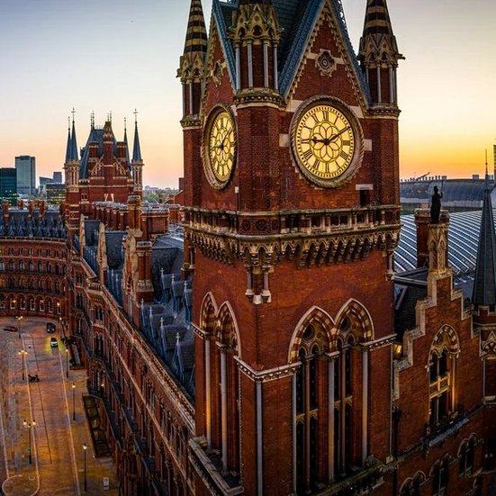 St Pancras Bahnhof Uhrturm bei Sonnenuntergang in London, mit warmen Farben und dramatischem Himmel.