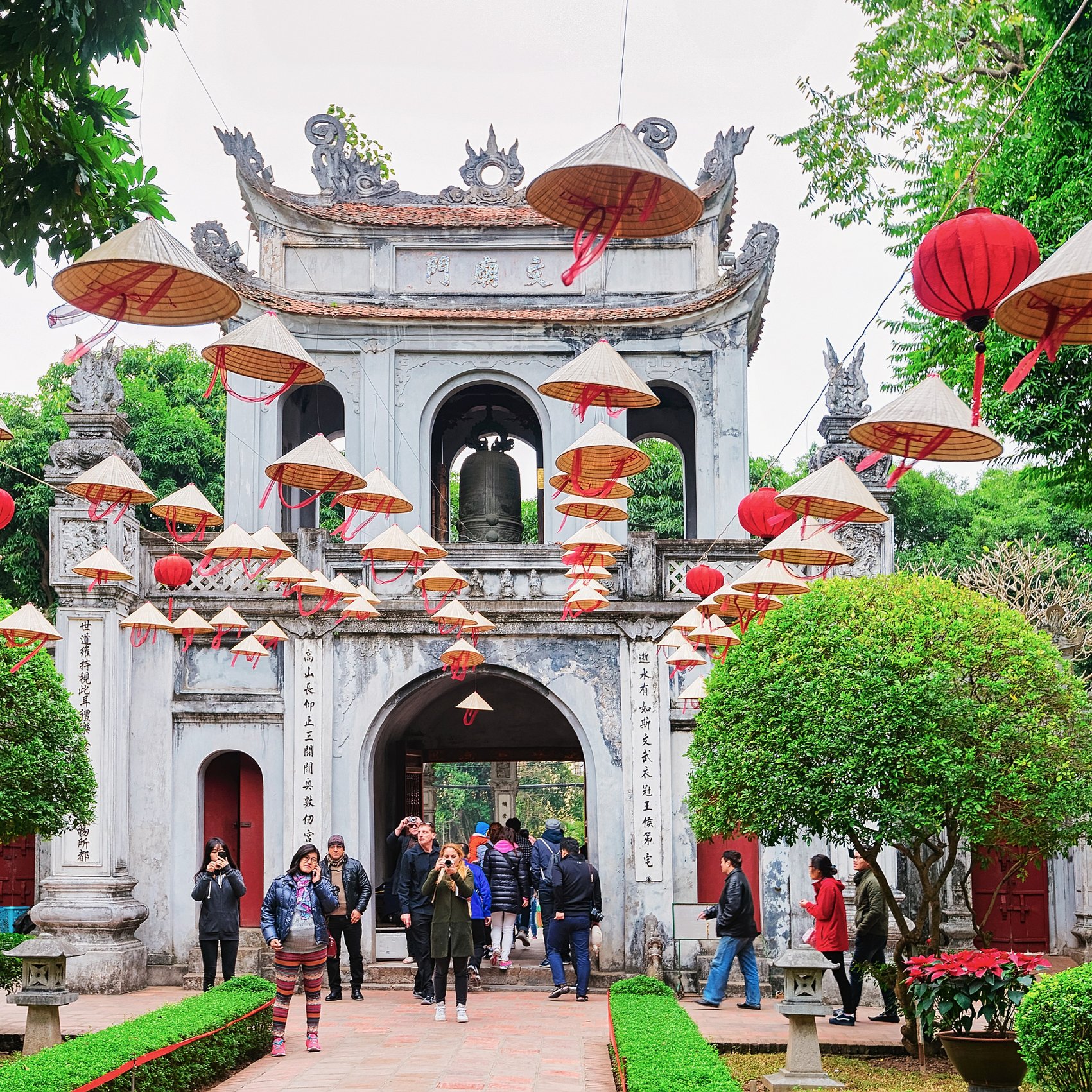Eingang des Literaturtempels in Hanoi mit traditionellen Hüten und Besuchern