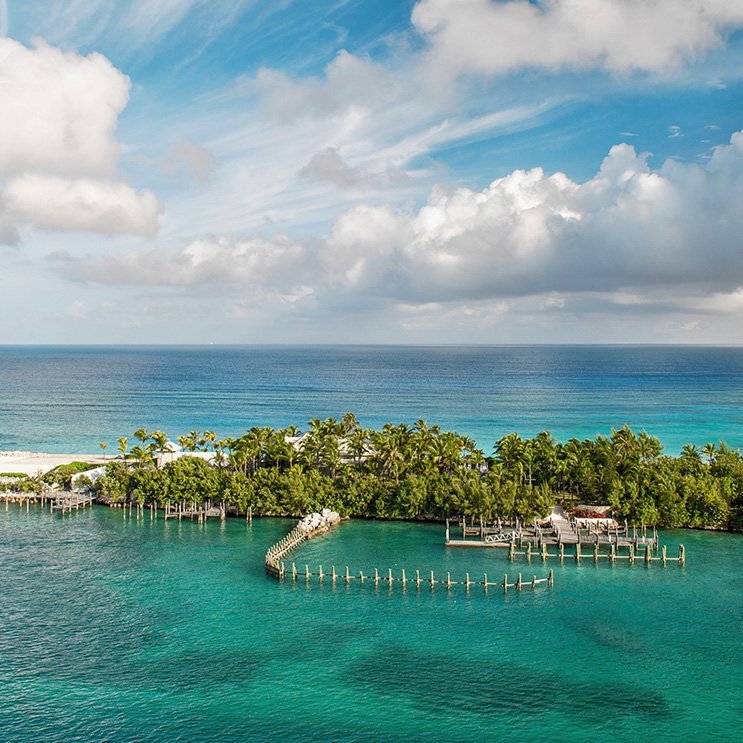 Bahamas-Insel mit einem Dock und einem weissen Haus, umgeben von klarem Wasser.