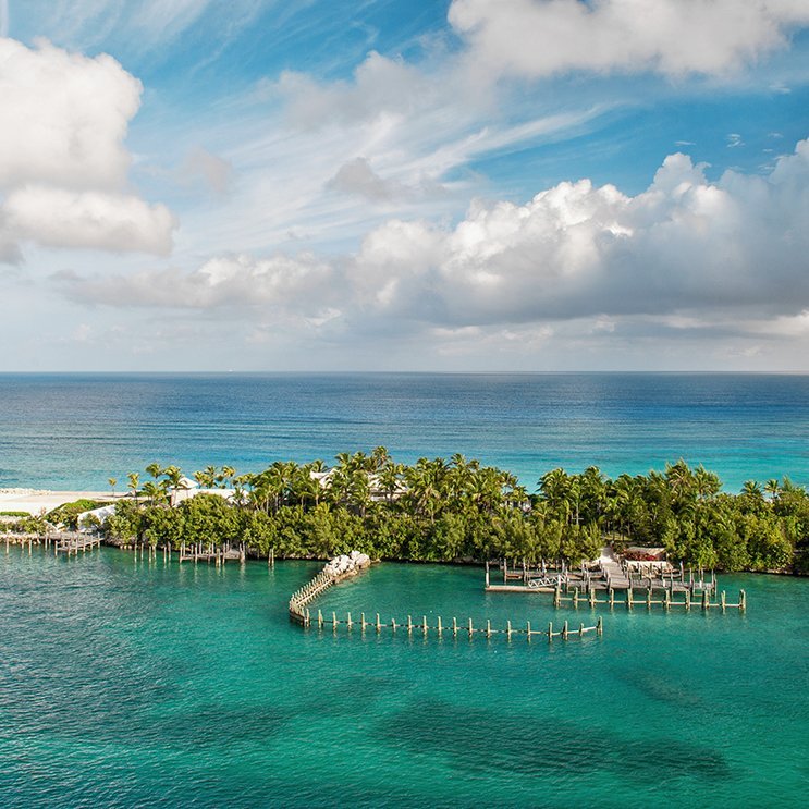 Île des Bahamas avec un quai et une maison blanche, entourée d'eau cristalline.