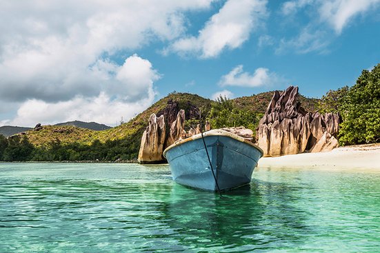 Boot auf dem Indischen Ozean, umgeben von blauem Wasser und weissem Sand.