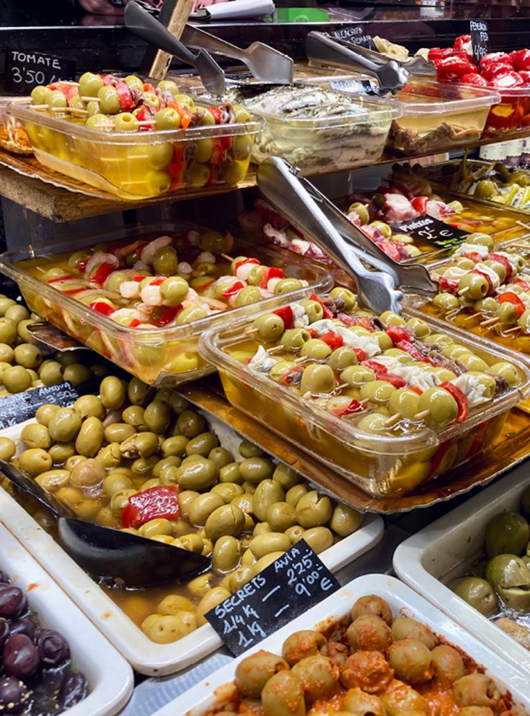 Oliven und verschiedene Lebensmittel auf einem Marktstand in der La Boqueria in Barcelona.