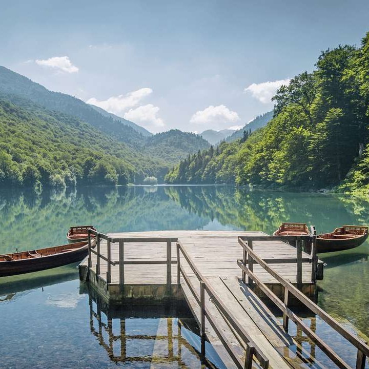 Zwei Boote liegen am Steg eines Sees in Montenegro, umgeben von majestätischen Bergen.