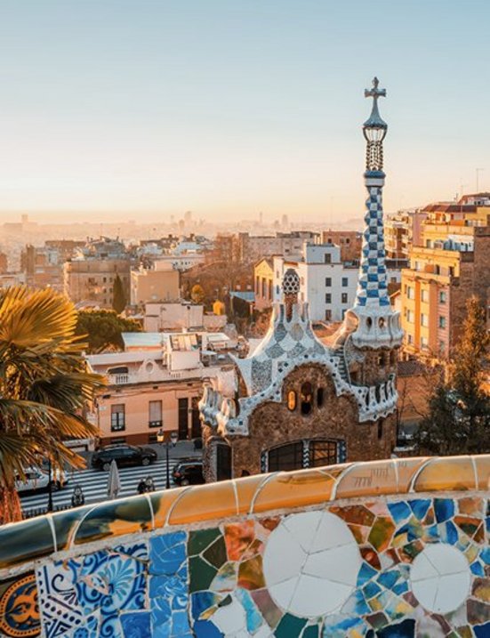 Barcelona bei Sonnenuntergang, mit leuchtenden Farben über der Stadt und silhouettierten Gebäuden im Hintergrund.