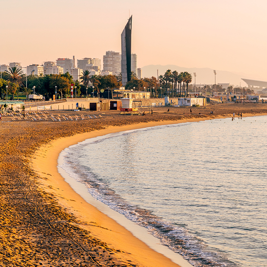 Ein Strand mit Wasser und der Stadt Barcelona im Hintergrund.