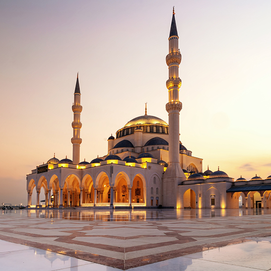 Grosses weisses Gebäude mit einem markanten Uhrturm in Dubai.