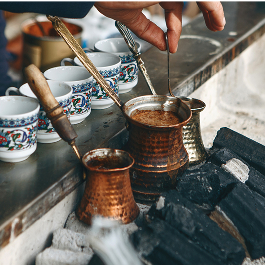 Eine Person giesst Kaffee in einen Kupfertopf in Istanbul.