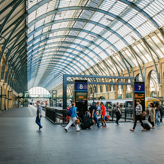 Eine Gruppe von Menschen spaziert durch einen belebten Bahnhof in London.