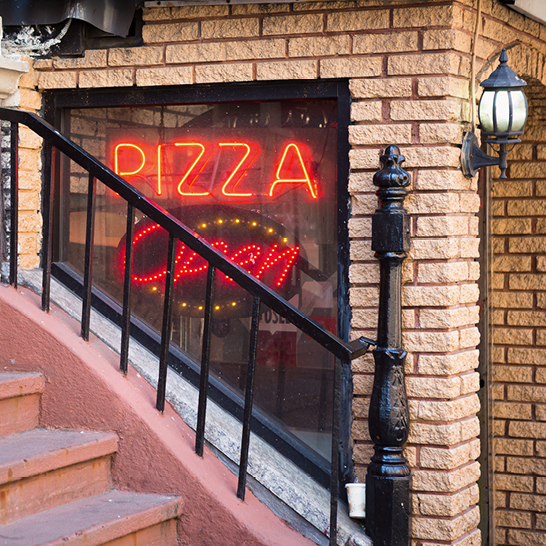 Rotes Neon-Schild an einem Backsteingebäude in NYC.