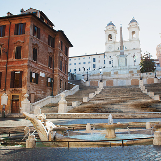 Ein Brunnen vor einem Gebäude mit einem Uhrturm am Rom Leben Plätze.
