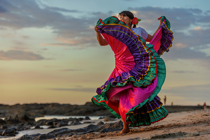 Une femme en robe colorée danse sur la plage ensoleillée du Costa Rica.