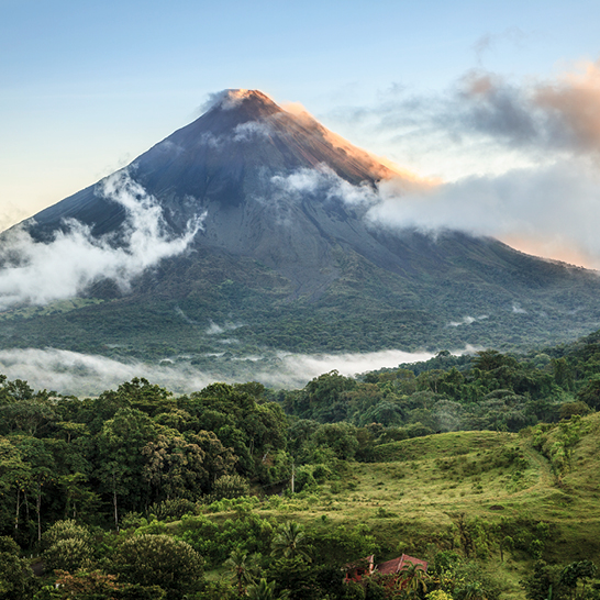 Volcan Arenal au Costa Rica, entouré de verdure luxuriante et de ciel bleu, symbole de la beauté naturelle du pays.