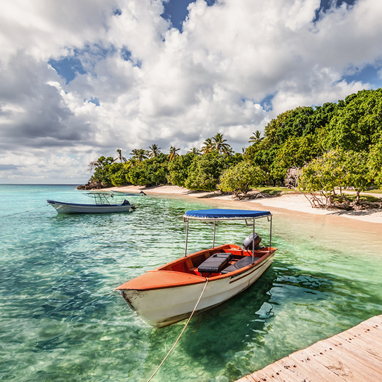 Ein Boot liegt am Strand in Samana, Dominikanische Republik, umgeben von feinem Sand und klarem Wasser.