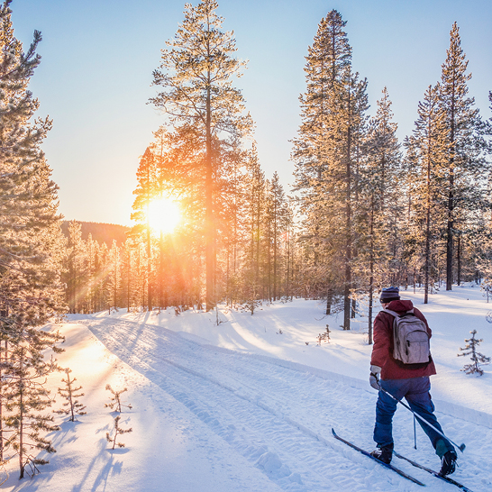  Ein Mann fährt bei Sonnenschein die verschneite Piste hinunter und genießt die Bewegung in Finnland.