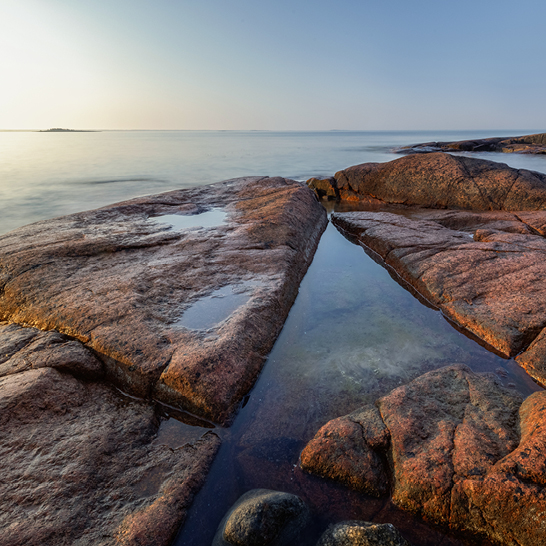 Felsen und Wasser bei Sonnenuntergang an der Küste der Åland-Inseln.