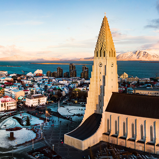 Blick auf Reykjavík, die Hauptstadt von Island, mit bunten Häusern und der beeindruckenden Hallgrímskirkja im Hintergrund.