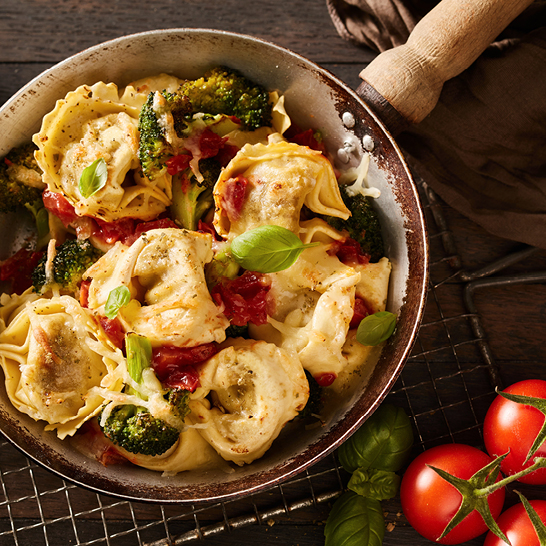 Eine Pfanne mit Pasta und buntem Gemüse, die italienische Aromen verspricht.