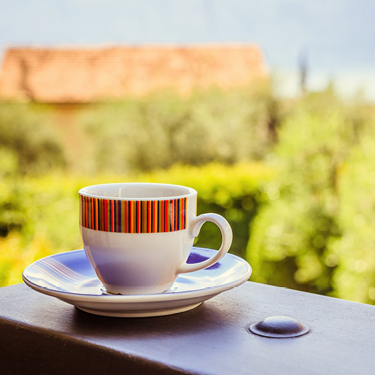 Eine Kaffeetasse mit Untertasse auf einem Tisch, umgeben von mediterranem Flair in Italien.