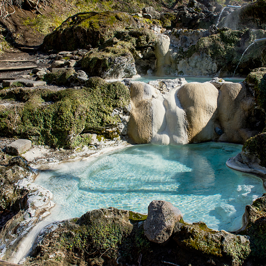 Wasserfall in einer felsigen Umgebung mit einem klaren Wasserbecken, Onsen, Japan.
