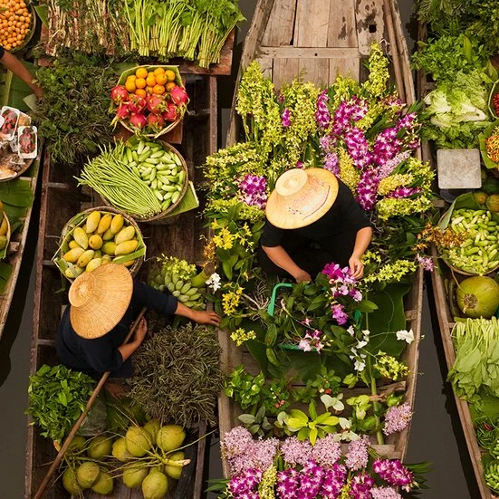 Schwimmender Markt in Thailand mit bunten Booten und frischen Produkten, die auf dem Wasser verkauft werden.