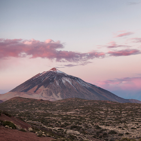 Teneriffa: Ein Berg unter einem rosa Himmel mit sanften Wolken.