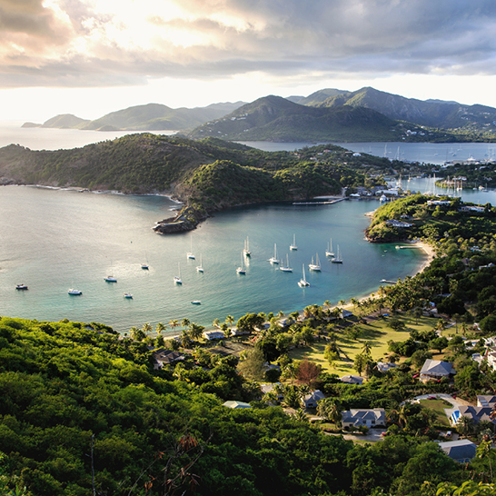 Blick auf eine Bucht mit Booten und einer beeindruckenden Bergkette der Kleinen Antillen.