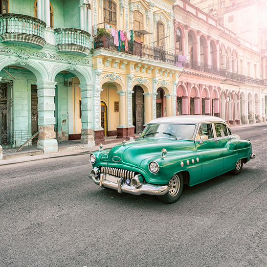 Ein alter grüner Wagen parkt auf einer Strasse in Kuba.