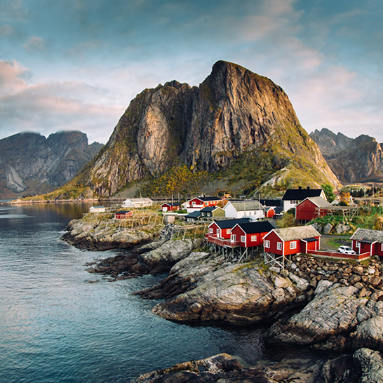 Wunderschöner Blick auf ein Küstendorf in Lofoten, umgeben von Bergen und klarem Wasser.