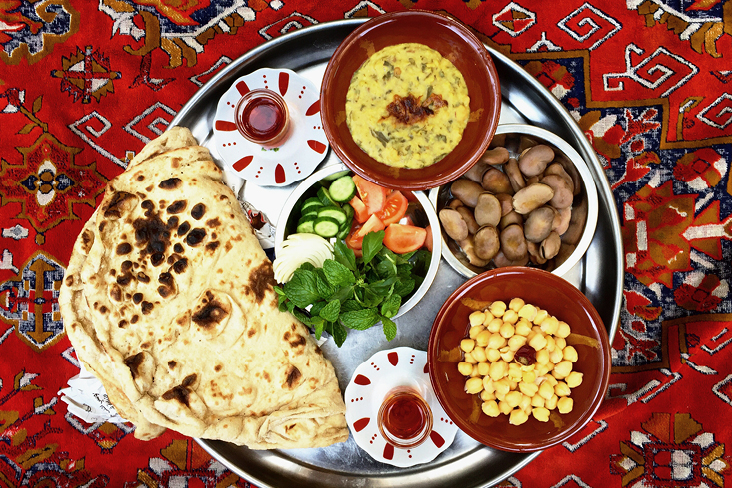 Ein Teller mit traditionellem Essen steht auf einem roten Teppich in Oman.