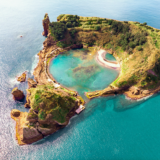 Luftaufnahme einer kleinen Insel mit einem blauen Pool in der Mitte.