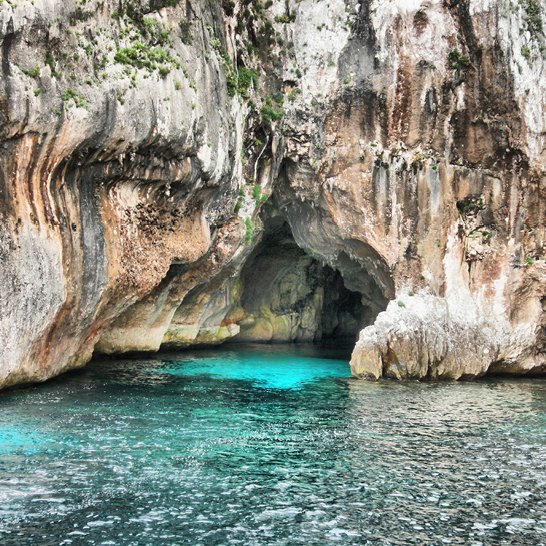 Die blaue See umgibt die Grotta Nettuno, eine beeindruckende Höhle an der Küste.